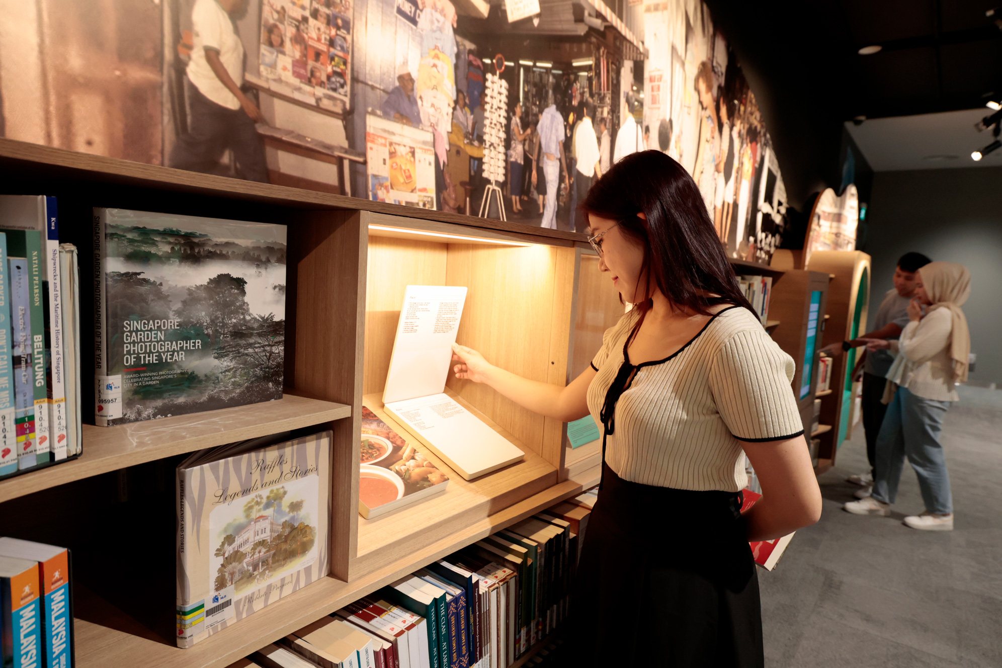 A photo of SG alcove space, a patron looking at one of the artefact presented at one of the section